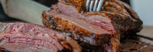 Person slicing grilled bison steak from an online meat market in Texas.